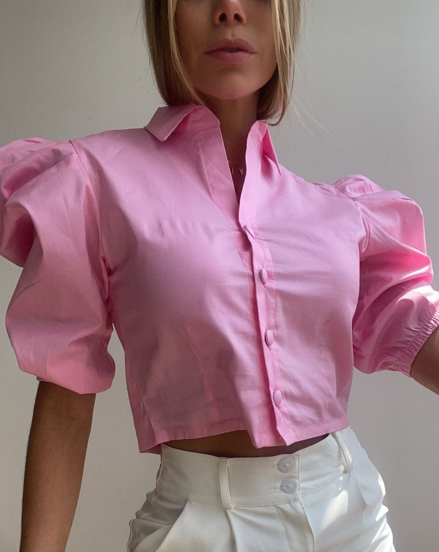 Mujer vistiendo una blusa crop top rosa con mangas abullonadas, ideal para un look chic y moderno. Disponible en KIKE RODRIGUEZ.