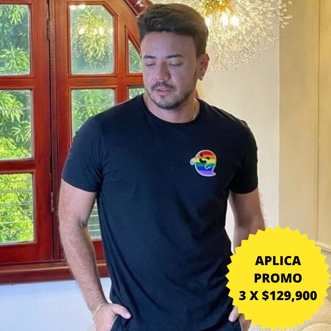 Camiseta negra con un pequeño estampado de arcoíris en el pecho. Perfecta para un look casual y elegante. Disponible en promoción de 3 por $129,900 en KIKE RODRIGUEZ. Ideal para mostrar apoyo a la diversidad.