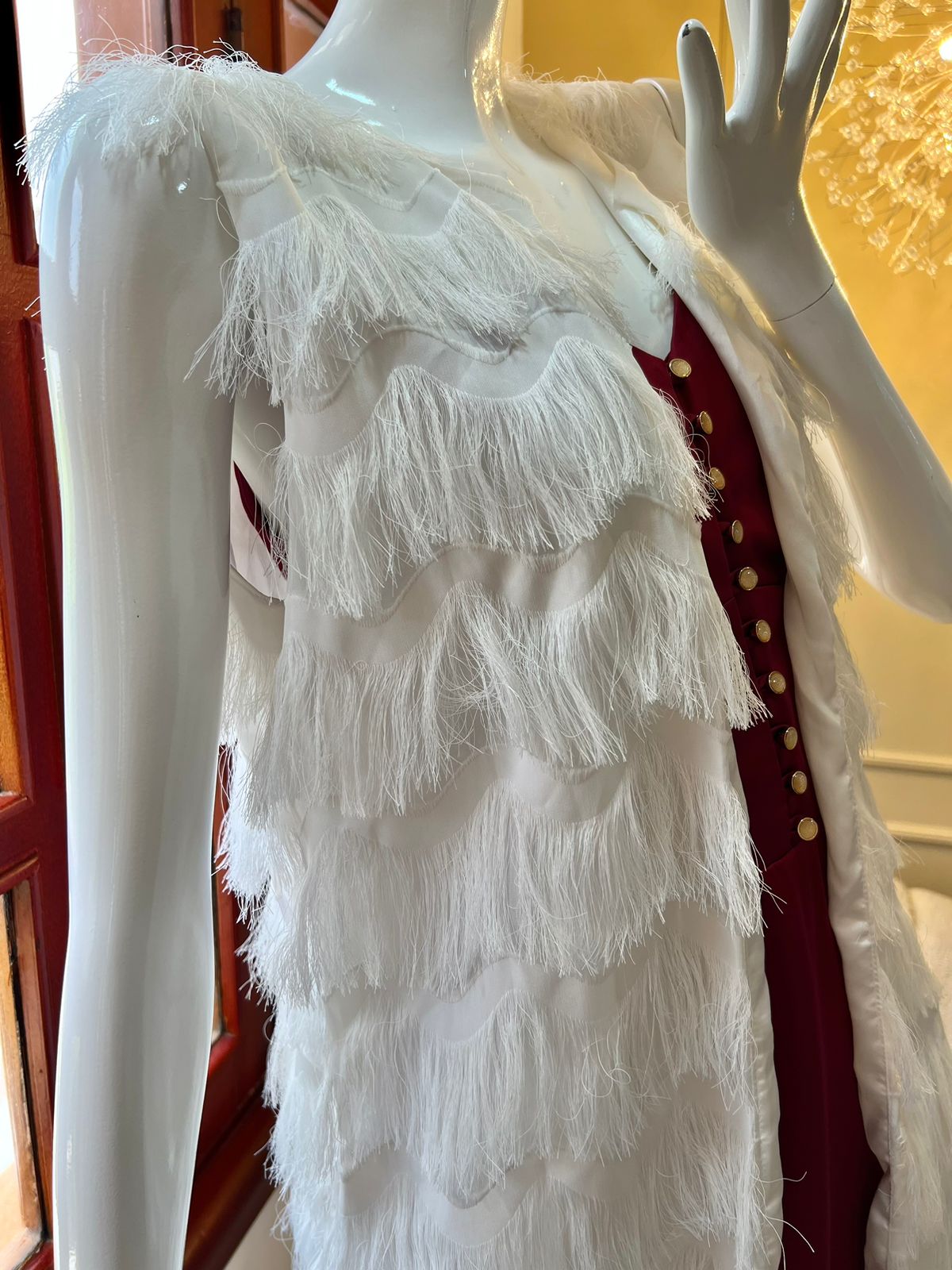 Maniquí luciendo un elegante chaleco blanco con flecos en capas, perfecto para añadir un toque de estilo bohemio y sofisticado a cualquier conjunto.