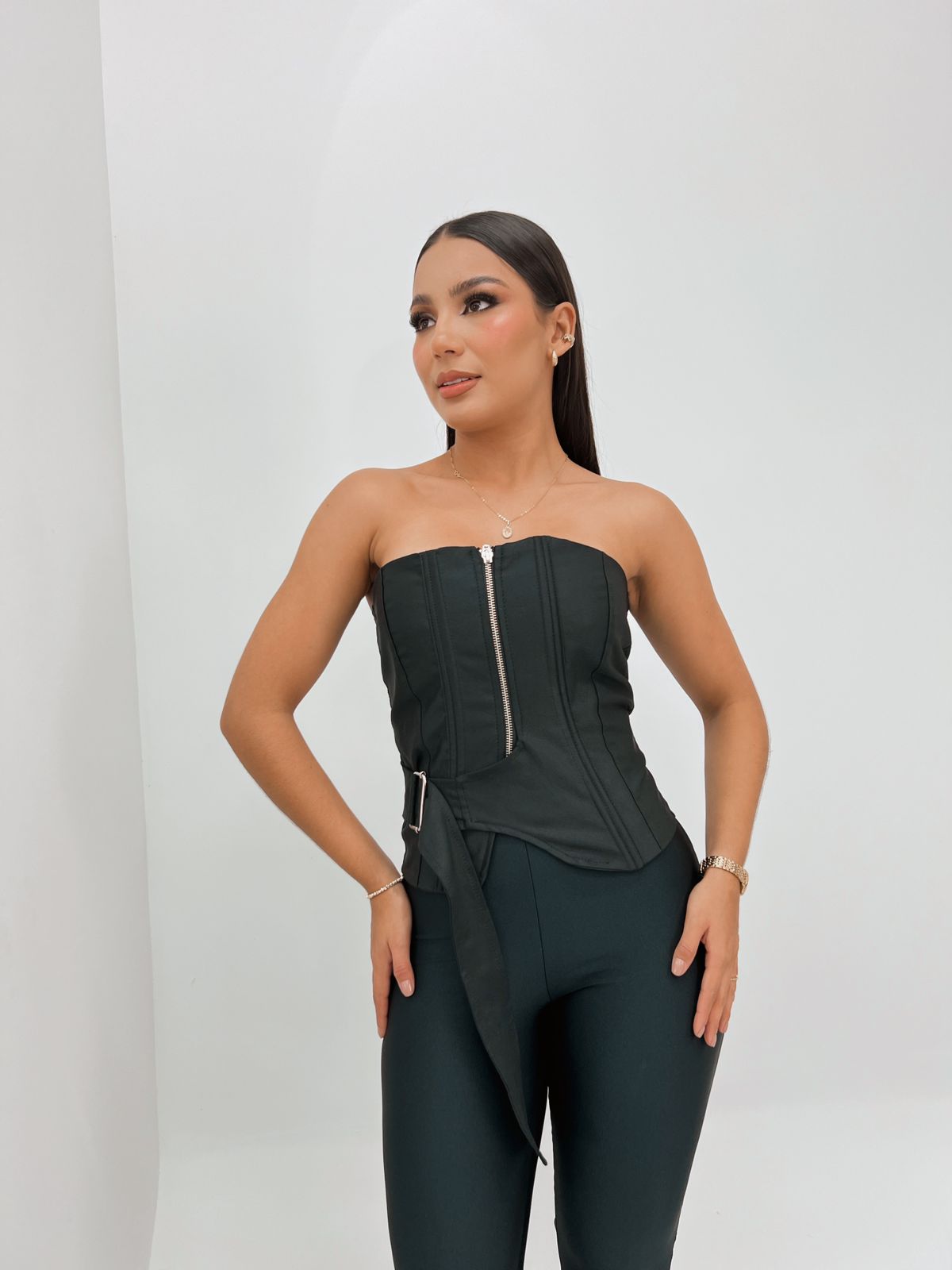 Top corset negro con cremallera frontal, ideal para un look sofisticado y moderno, combinado con pantalones ajustados para resaltar la figura.