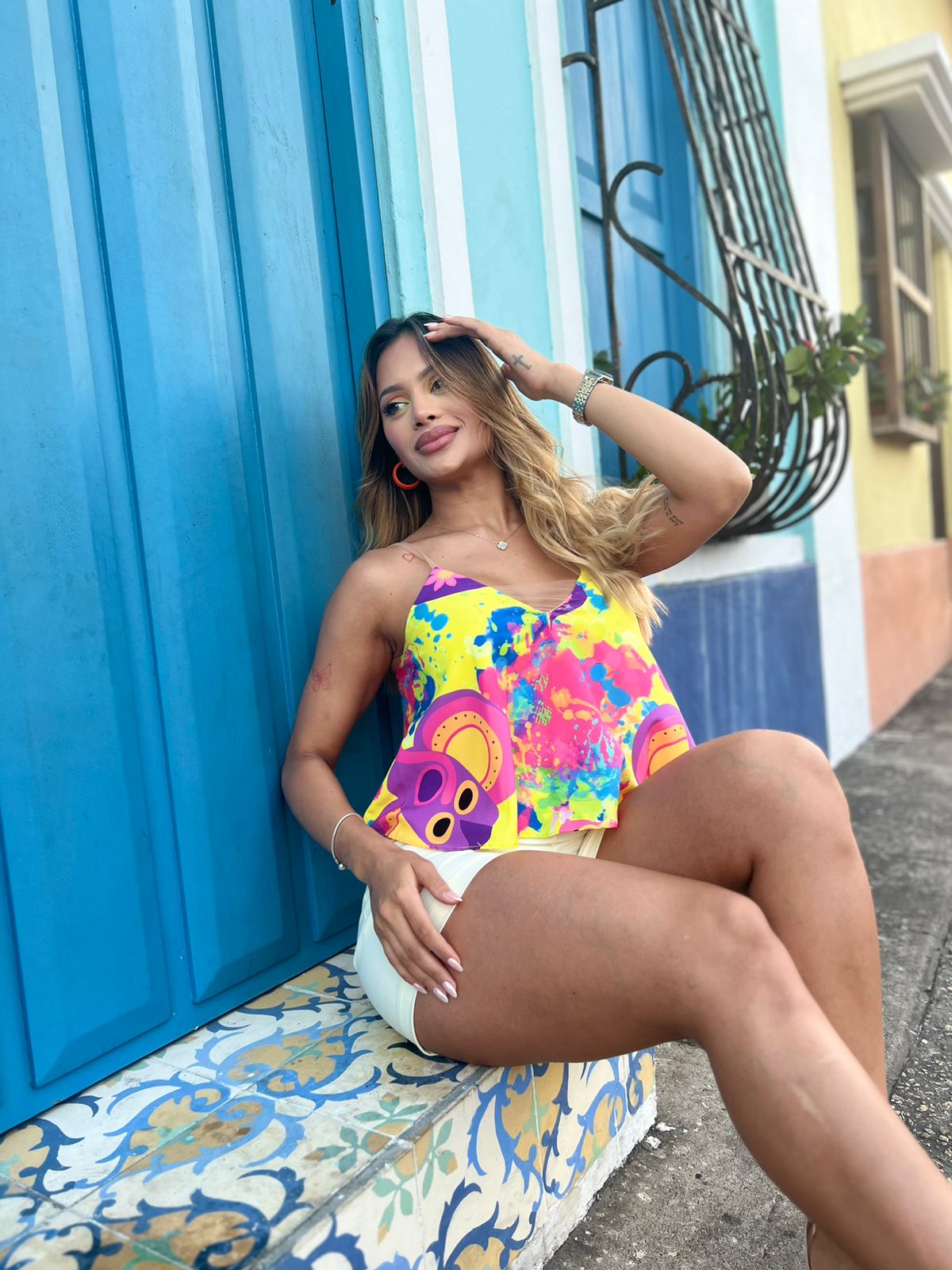 Mujer vistiendo un top de tirantes con estampado colorido de KIKE RODRIGUEZ, ideal para un look veraniego y vibrante. Perfecto para destacar en cualquier ocasión especial.