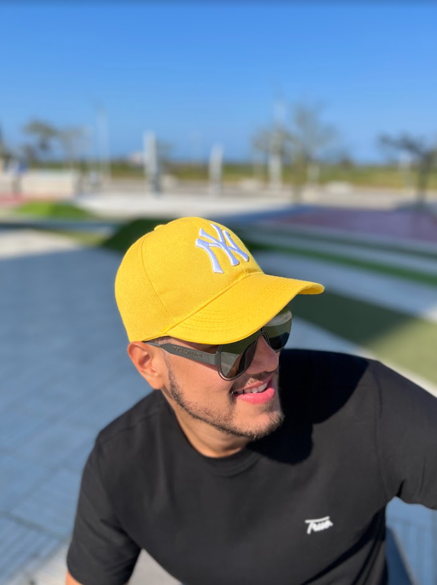 Hombre sonriente con gorra deportiva NY de color amarillo, modelo de KIKE RODRIGUEZ, ideal para un look casual y moderno.