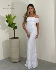 Modelo luciendo un vestido blanco de encaje con diseño off-shoulder de KIKE RODRIGUEZ. Vestido elegante y ajustado, ideal para eventos formales y ocasiones especiales, destacando por su estilo sofisticado y femenino.