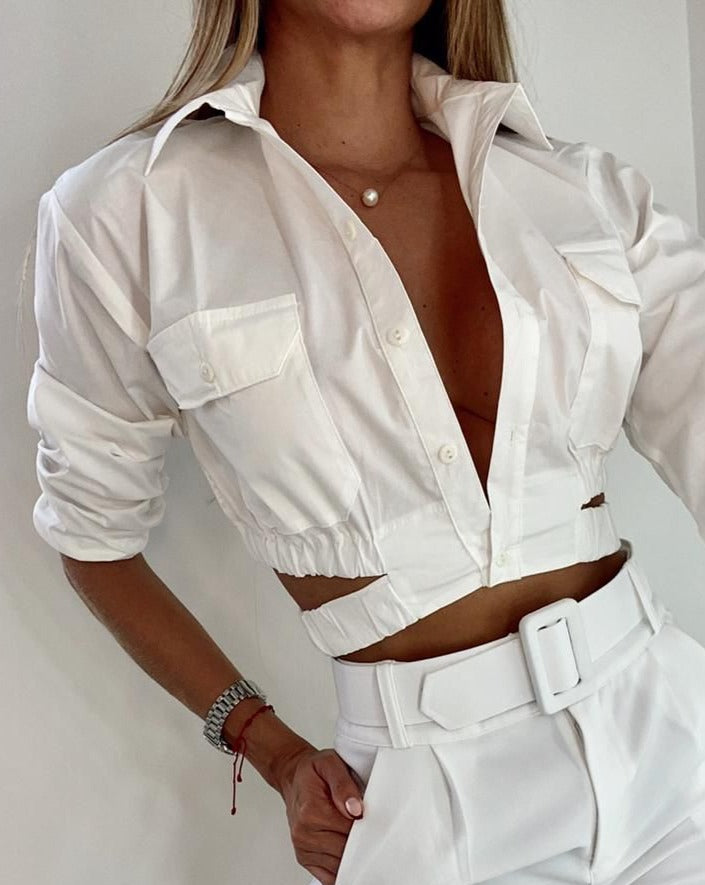 Mujer vistiendo una elegante blusa blanca crop con detalles y cinturón, perfecta para un look moderno y sofisticado. Disponible en KIKE RODRIGUEZ.