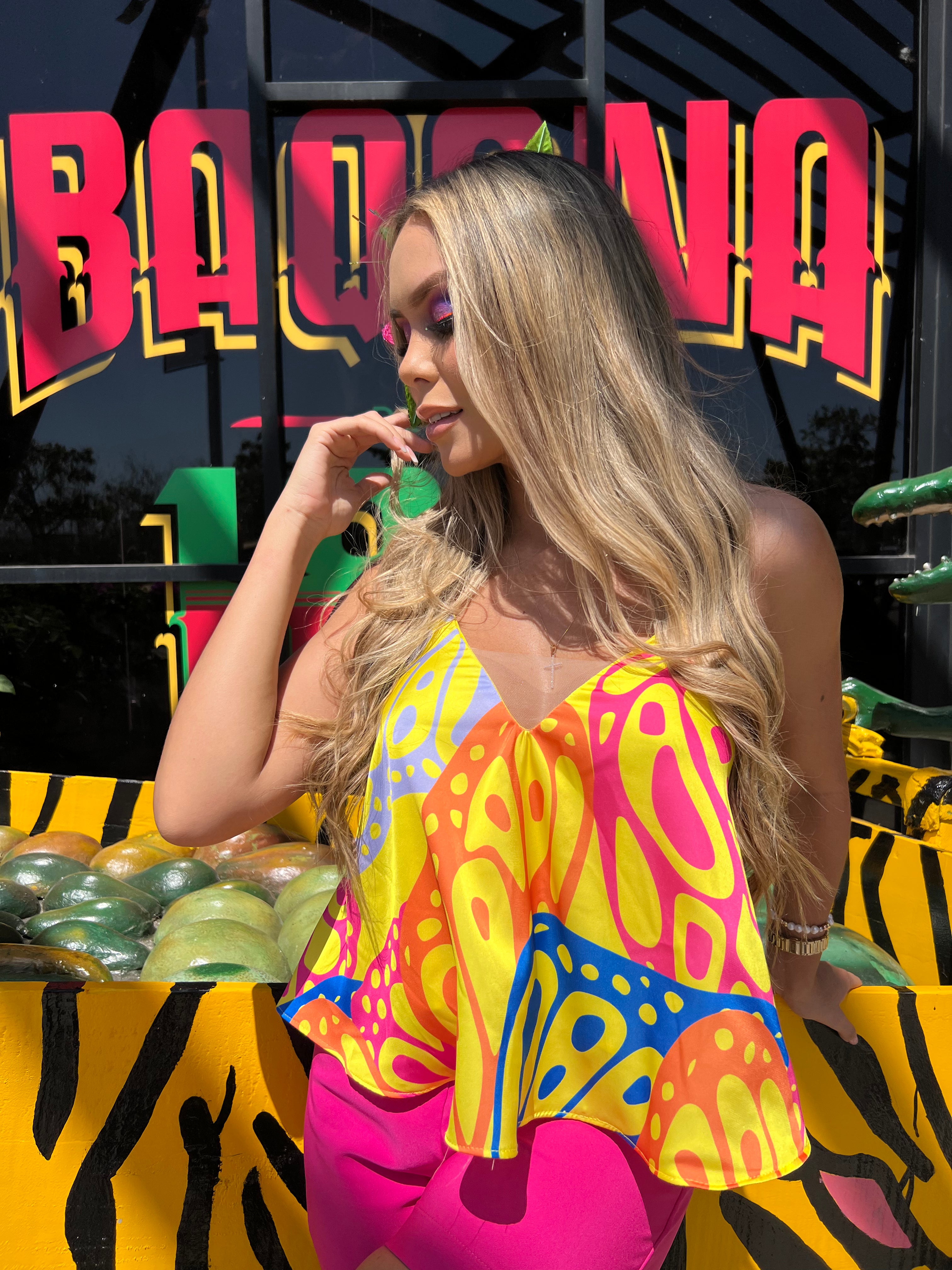 Mujer luciendo una blusa estampada colorida con tirantes finos, ideal para un look vibrante y alegre. Perfecta para destacar en cualquier ocasión.