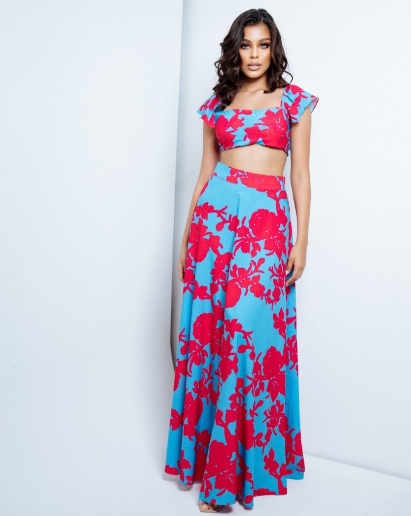 Mujer vistiendo un conjunto de top y falda floral en azul y rosa de KIKE RODRIGUEZ, disponible con descuento exclusivo. Ideal para lucir elegante y fresca.